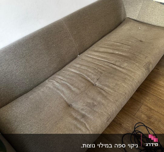 ספה חומה עם קמטים על רצפת עץ
